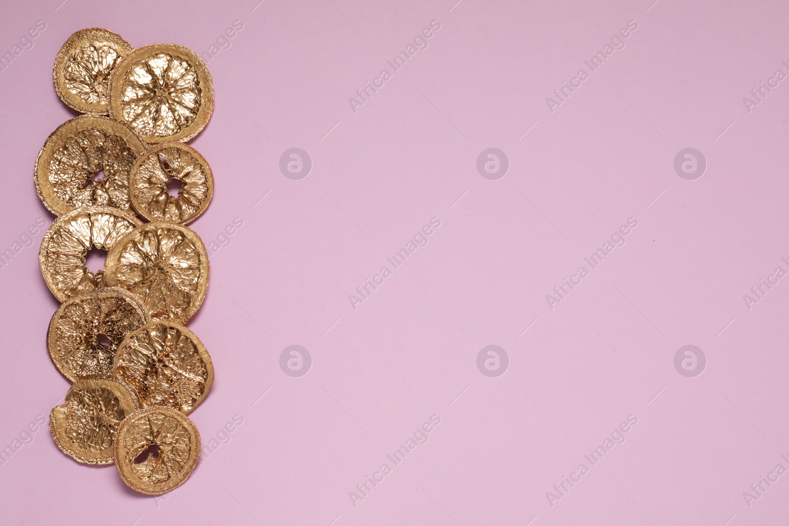 Photo of Golden lemon slices on pink background, flat lay. Space for text