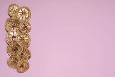 Photo of Golden lemon slices on pink background, flat lay. Space for text