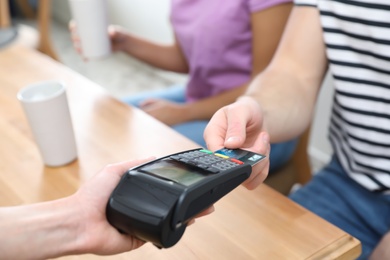 Photo of Client using credit card machine for non cash payment indoors, closeup