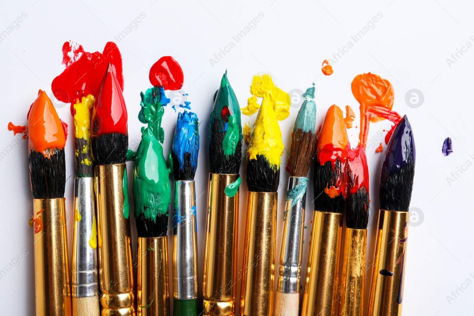 Photo of Brushes with colorful paints on white background, flat lay