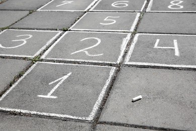 Hopscotch drawn with white chalk on street tiles outdoors