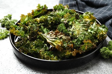 Tasty baked kale chips on grey table