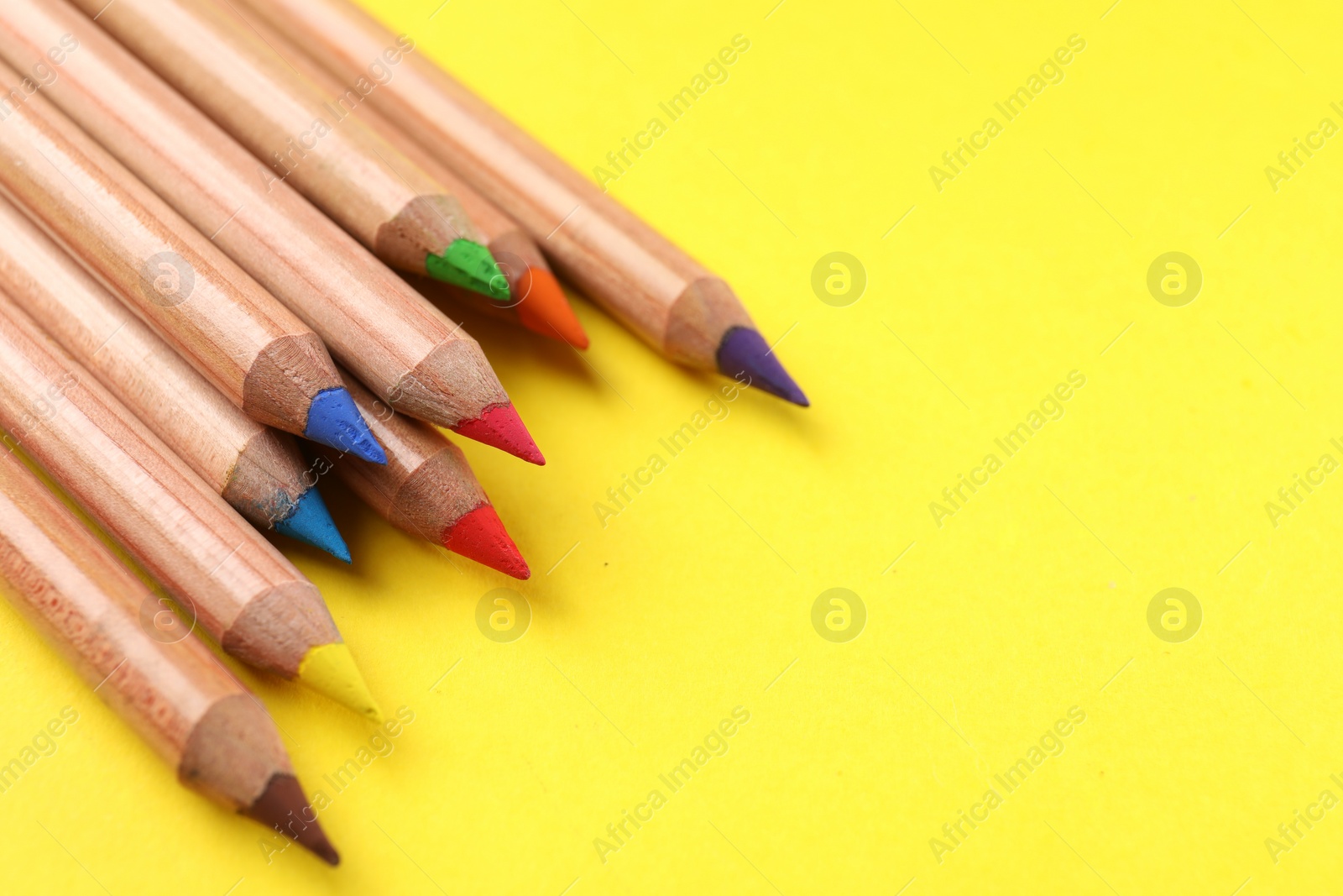 Photo of Many colorful pastel pencils on yellow background, closeup and space for text. Drawing supplies