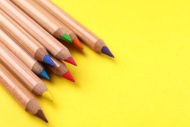 Many colorful pastel pencils on yellow background, closeup and space for text. Drawing supplies