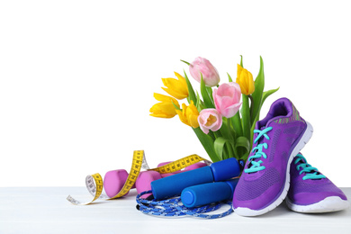 Photo of Composition with spring flowers and sports items on wooden table against white background