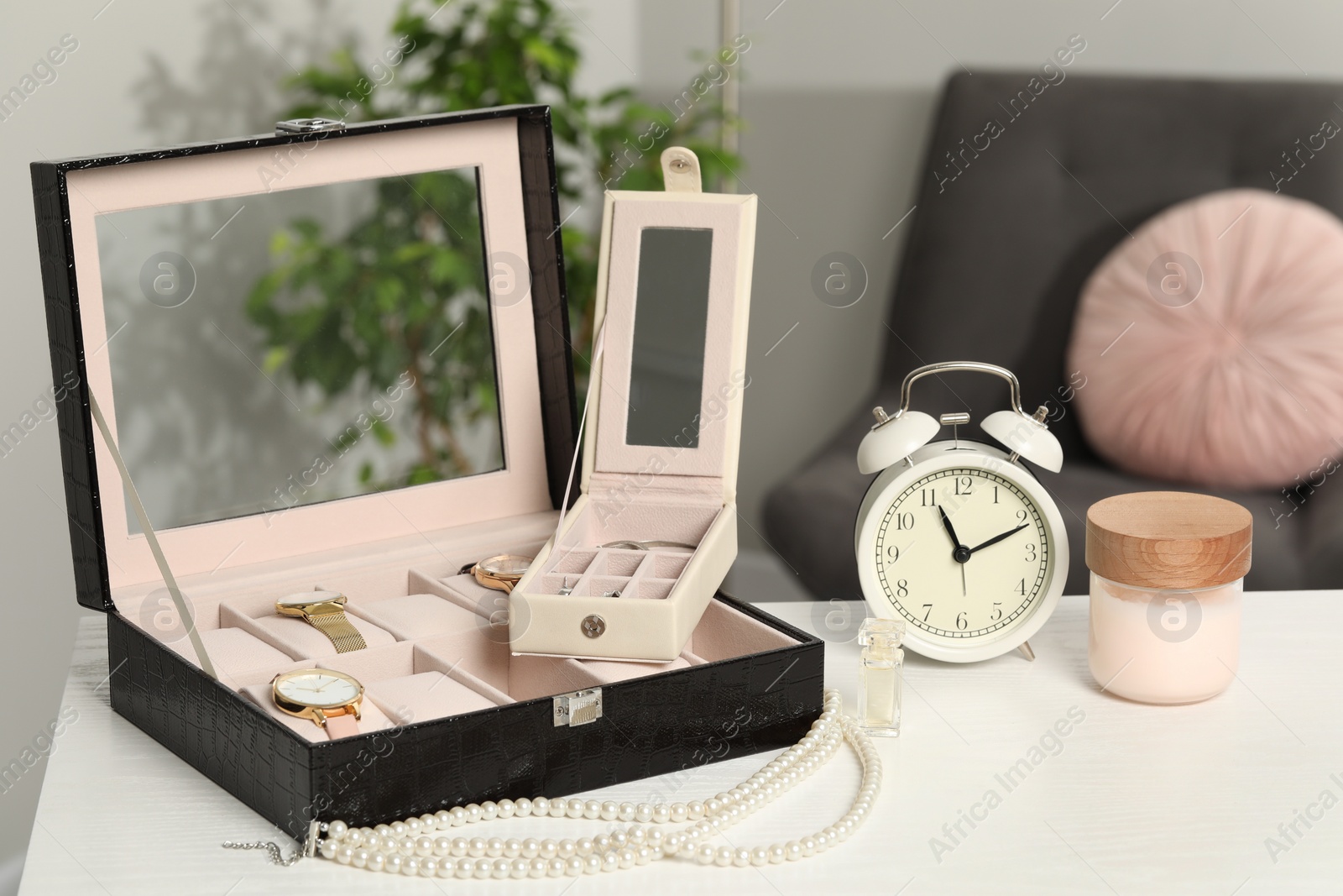 Photo of Jewelry boxes with many stylish wristwatches, accessories, alarm clock and perfume on white wooden table indoors