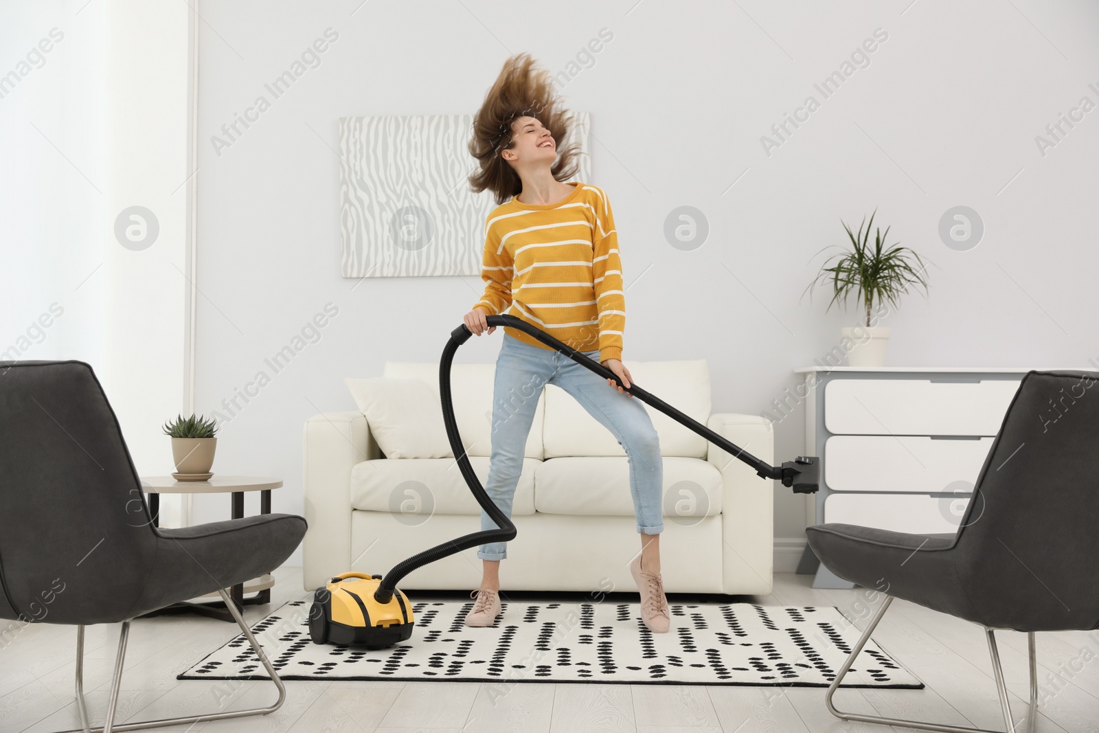 Photo of Young woman having fun while vacuuming at home