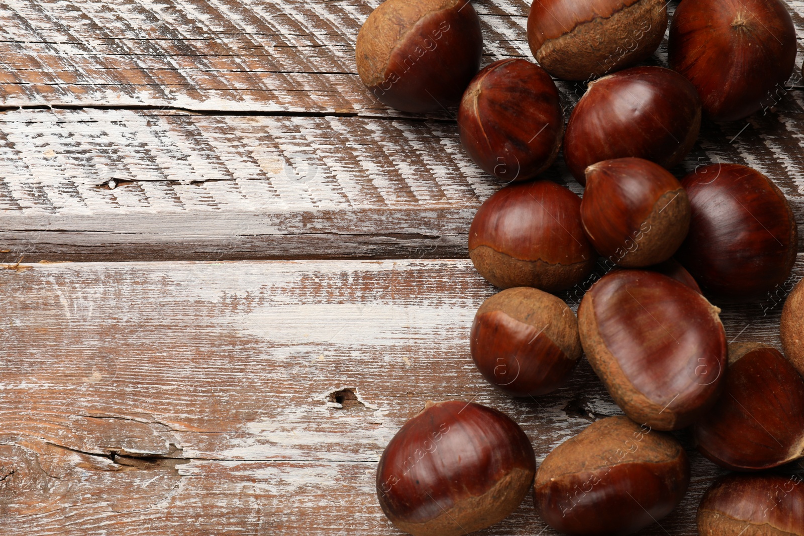 Photo of Sweet fresh edible chestnuts on wooden table, top view. Space for text