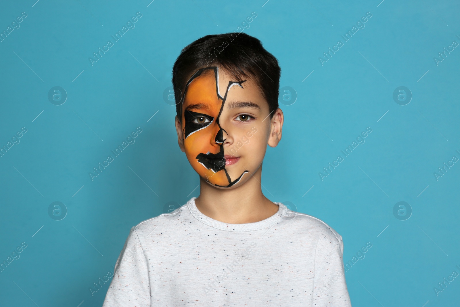 Photo of Cute little boy with face painting on blue background