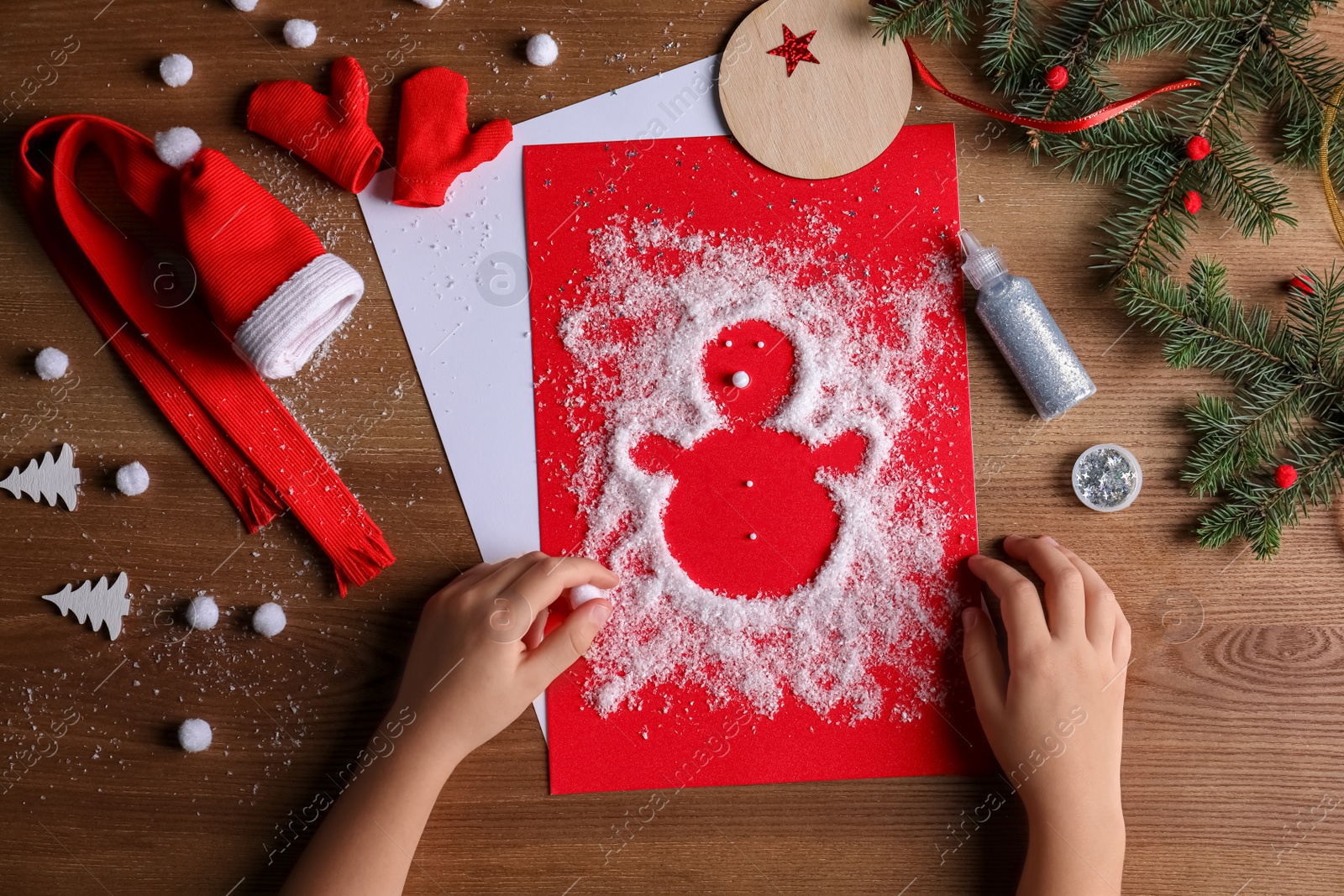 Photo of Little child making Christmas card at wooden table, top view