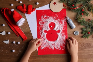 Little child making Christmas card at wooden table, top view