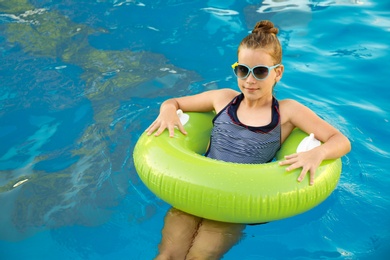 Happy little girl with inflatable ring in swimming pool