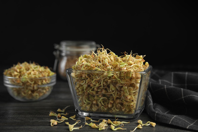 Photo of Glass bowl of sprouted green buckwheat on dark wooden table