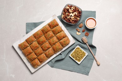 Delicious sweet baklava with ingredients on light grey marble table, flat lay