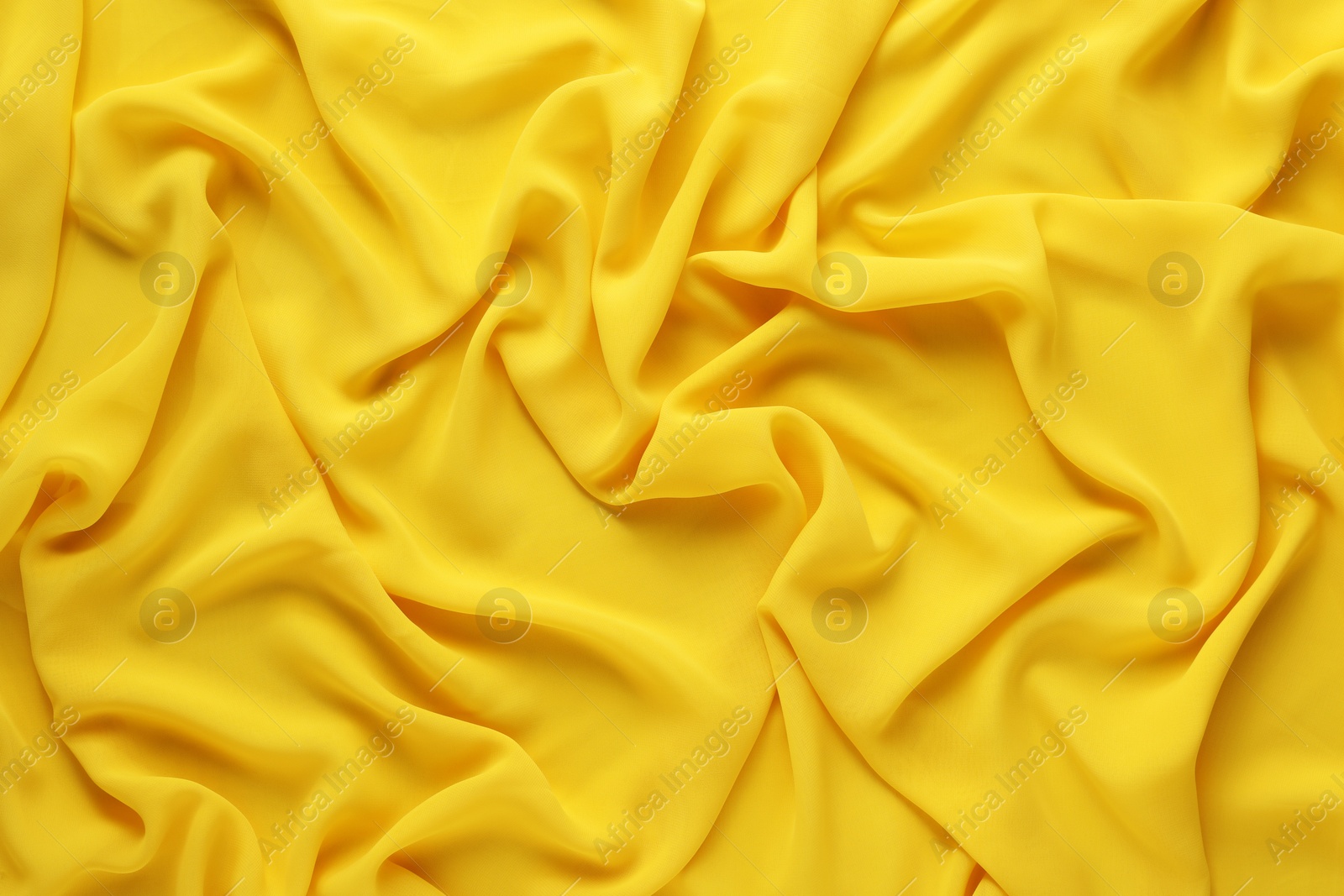 Photo of Beautiful yellow tulle fabric as background, top view