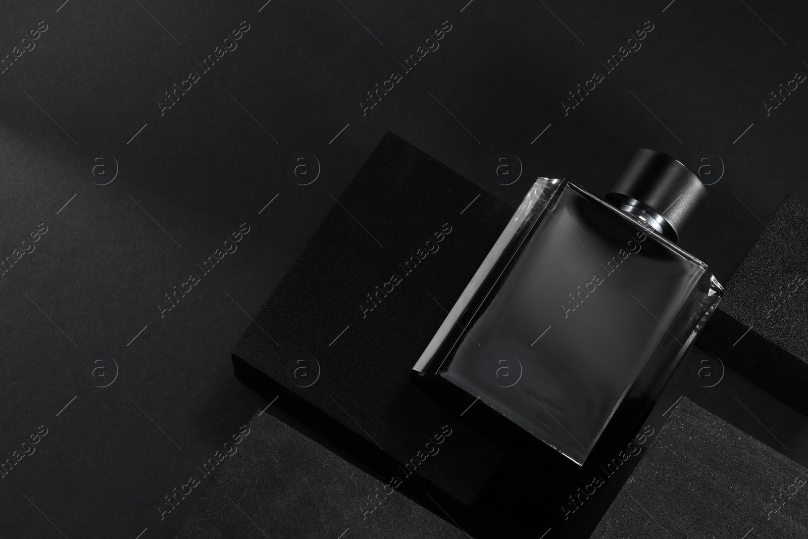 Photo of Stylish presentation of luxury men`s perfume in bottle on black background, top view. space for text