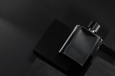 Photo of Stylish presentation of luxury men`s perfume in bottle on black background, top view. space for text