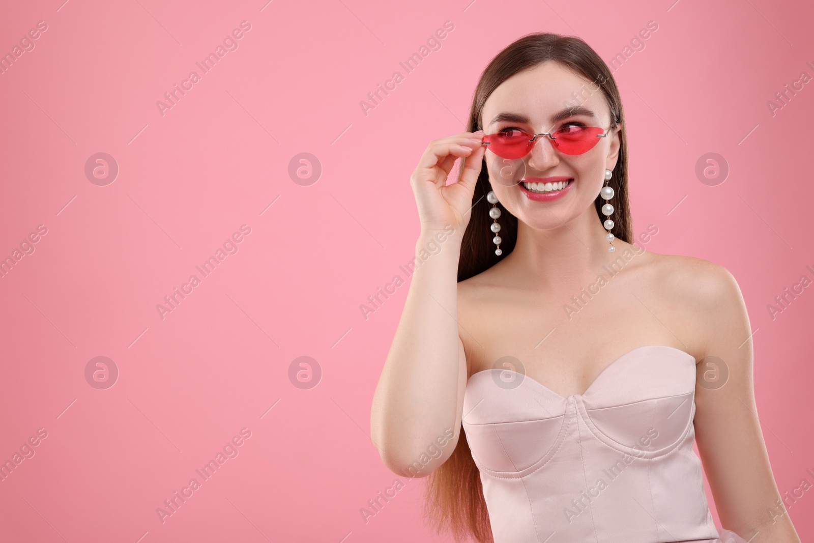 Photo of Pink look. Beautiful woman in clothes and bright sunglasses on color background, space for text