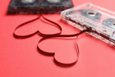 Photo of Music cassettes and hearts made with tape on red background, closeup. Listening love songs