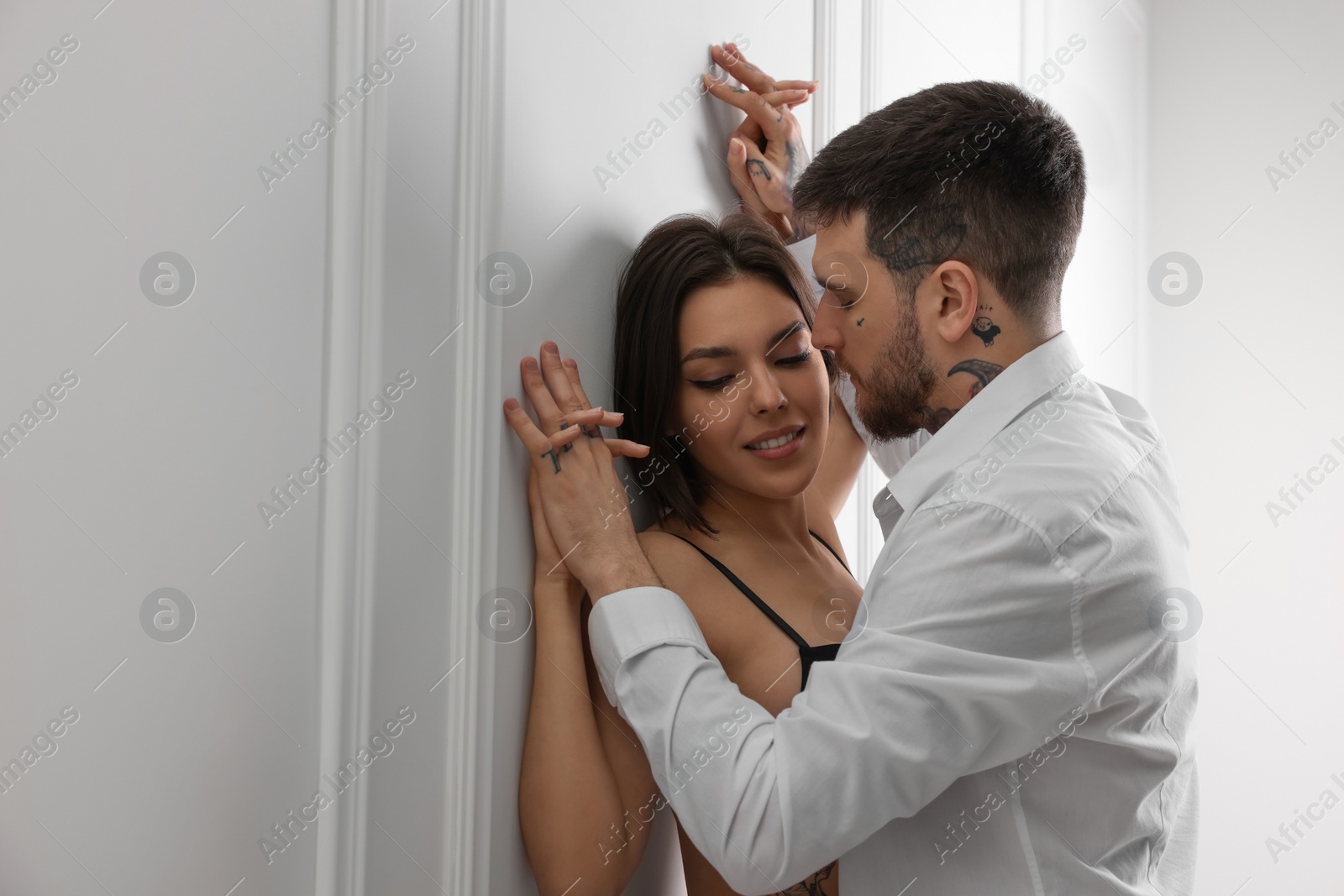 Photo of Passionate couple having sex near white wall indoors, space for text