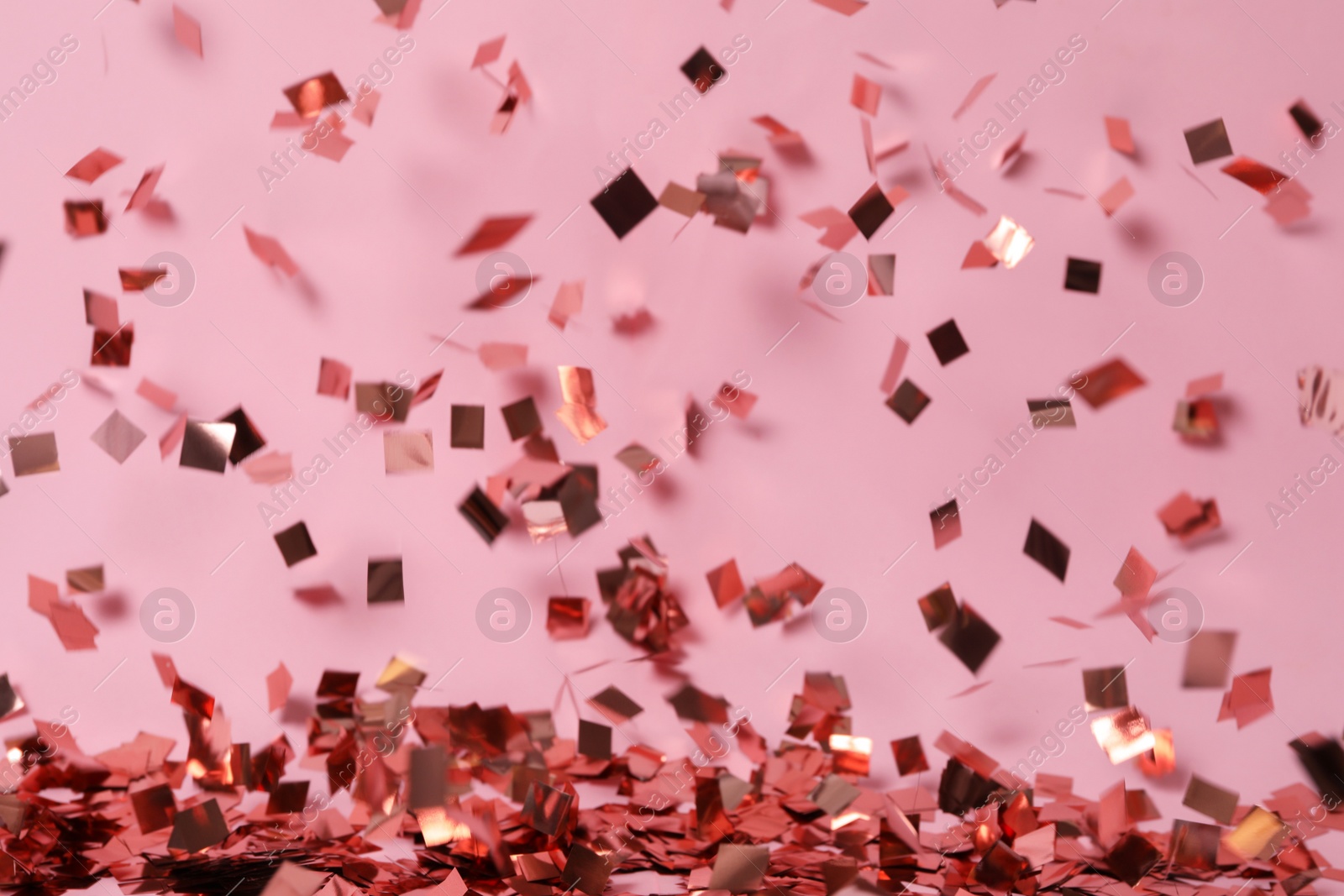 Photo of Shiny confetti falling down on pink background