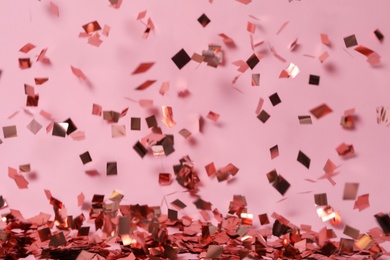 Shiny confetti falling down on pink background