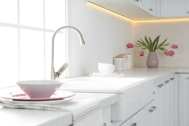 Photo of Beautiful ceramic dishware and bouquet on countertop in kitchen