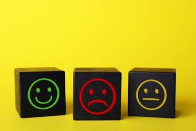 Image of Complaint. Black wooden cubes with sad, happy and neutral faces