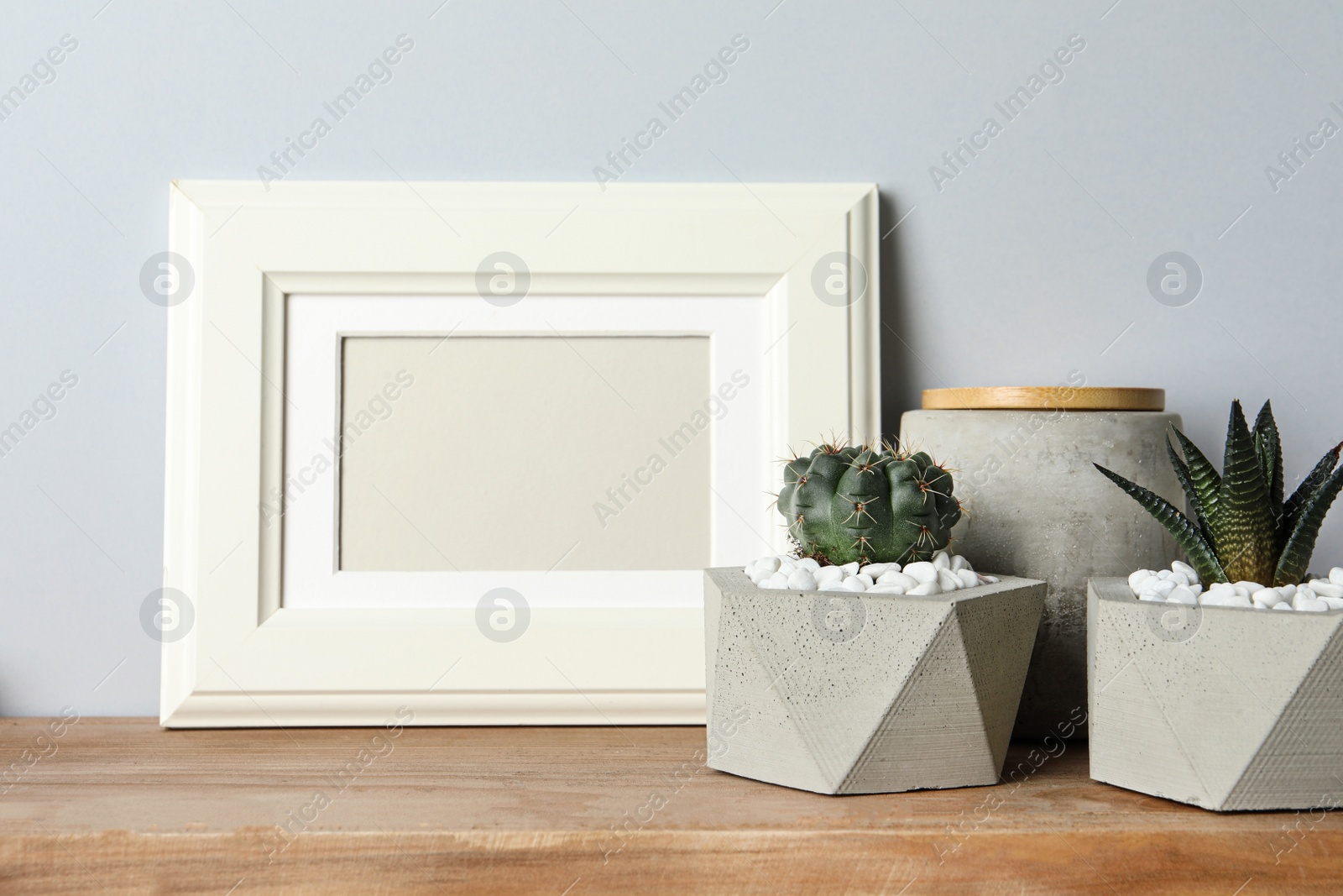 Photo of Blank frame and beautiful succulent plants on table against light background, space for design. Home decor