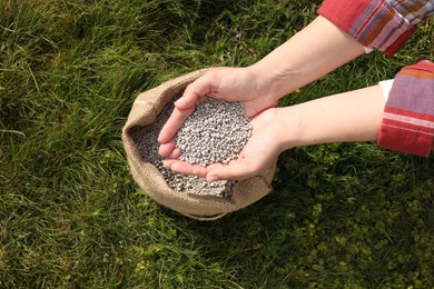 Woman with fertilizer on green grass outdoors, top view