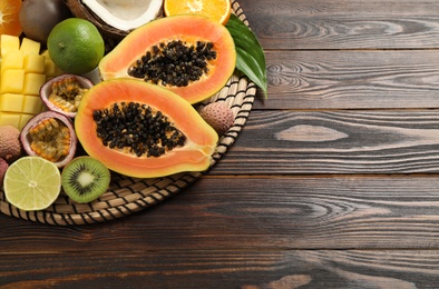 Photo of Fresh ripe papaya and other fruits on wooden table, above view. Space for text