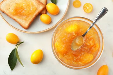 Delicious kumquat jam, fresh fruits and sandwich on white table, flat lay
