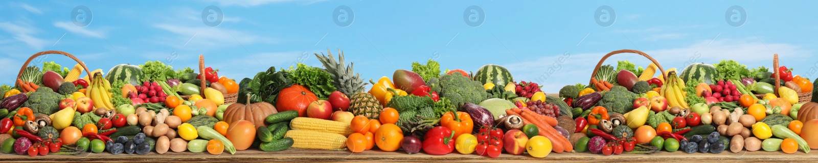 Image of Assortment of fresh organic fruits and vegetables on wooden table outdoors. Banner design