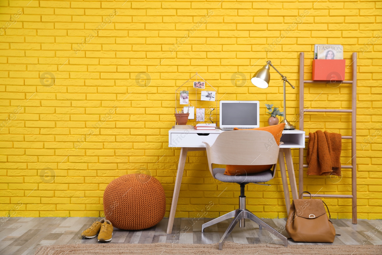 Photo of Stylish home office interior with comfortable workplace near yellow brick wall. Space for text