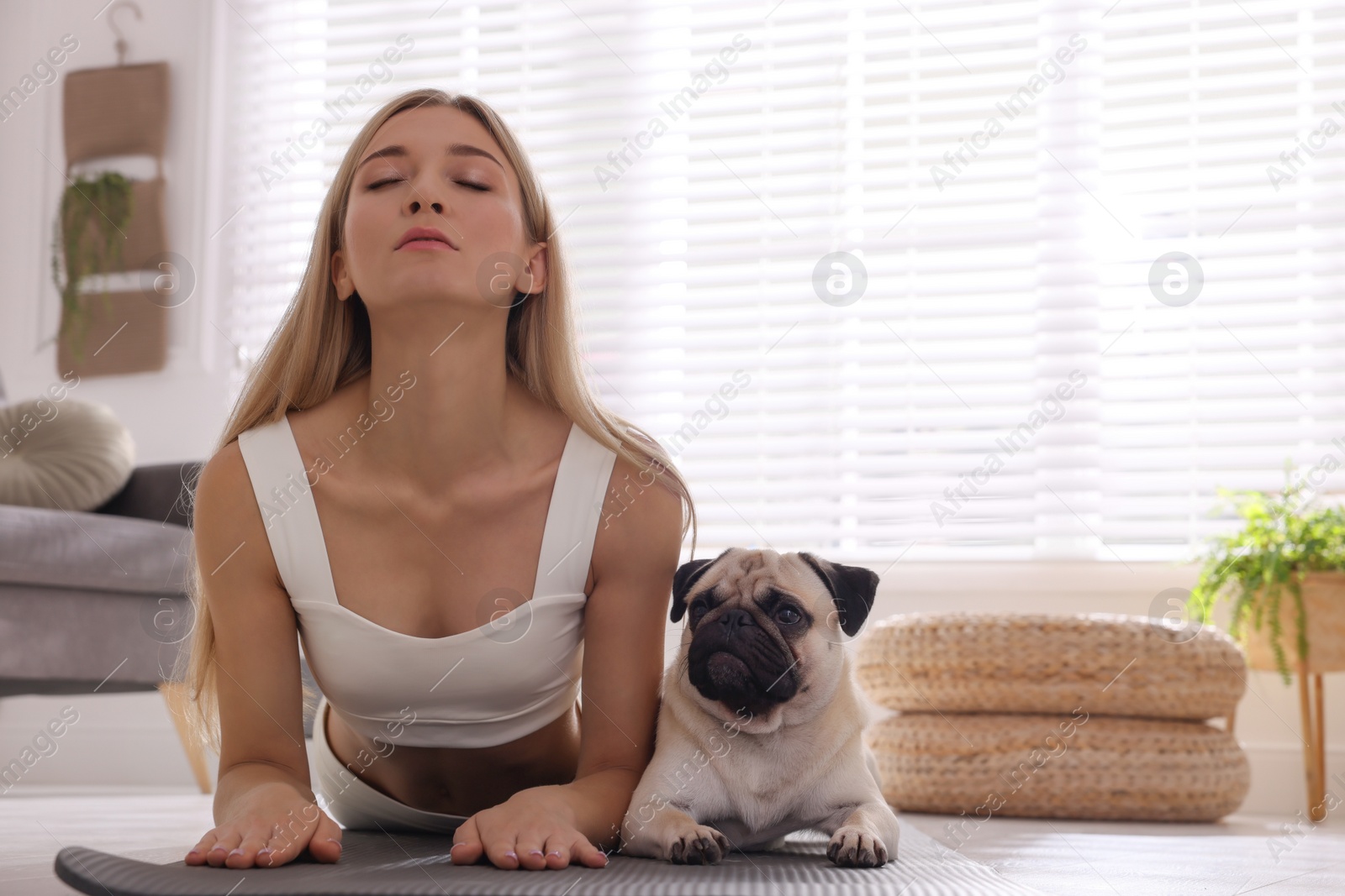 Photo of Beautiful woman with dog practicing yoga at home