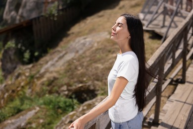 Photo of Feeling freedom. Beautiful woman enjoying nature near wooden railing in mountains