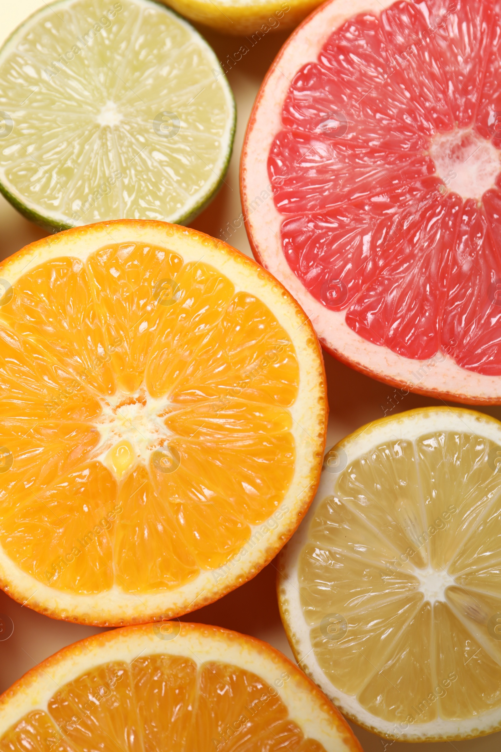 Photo of Different cut citrus fruits on beige table, flat lay