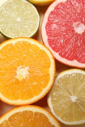 Photo of Different cut citrus fruits on beige table, flat lay