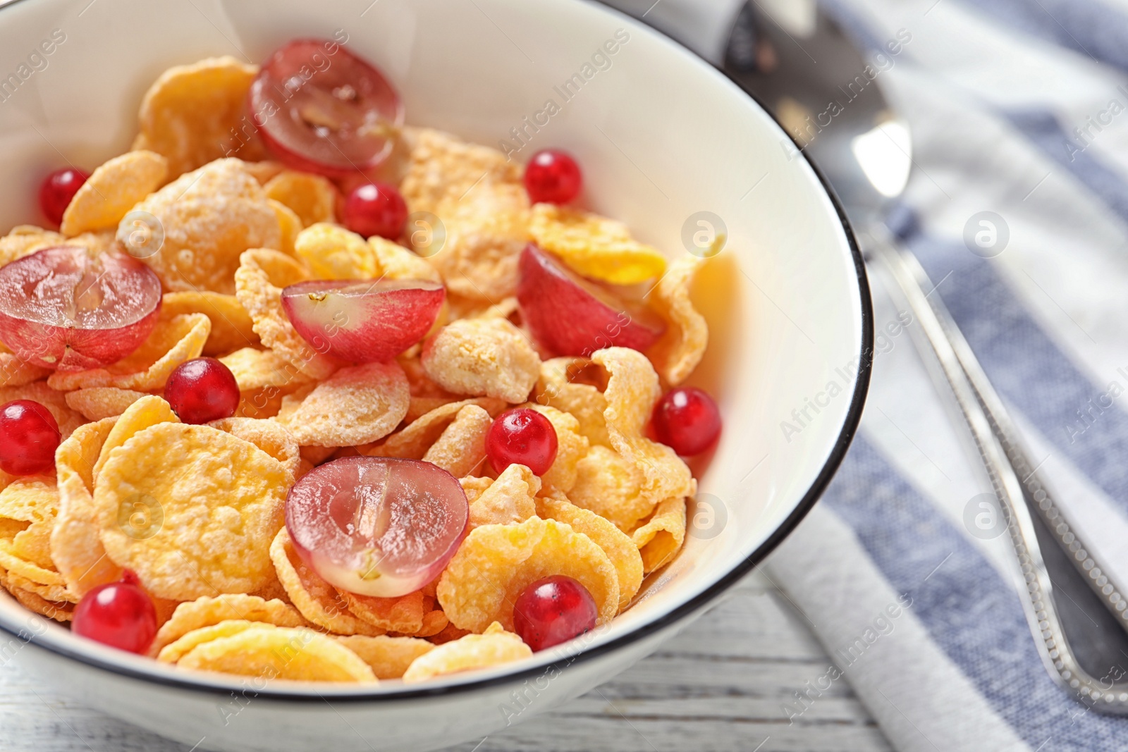 Photo of Corn flakes with berries on table, closeup. Healthy breakfast
