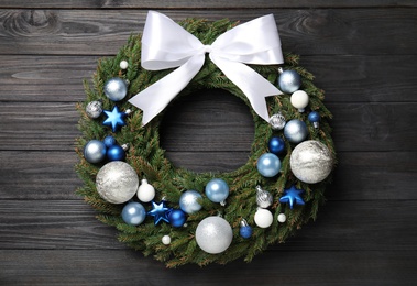 Photo of Beautiful Christmas wreath on black wooden background, top view