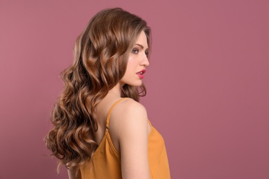 Photo of Portrait of young woman with long beautiful hair on color background