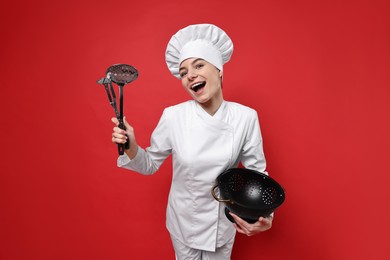 Professional chef with kitchen utensils having fun on red background