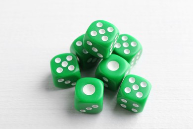 Many green game dices on white wooden table, above view