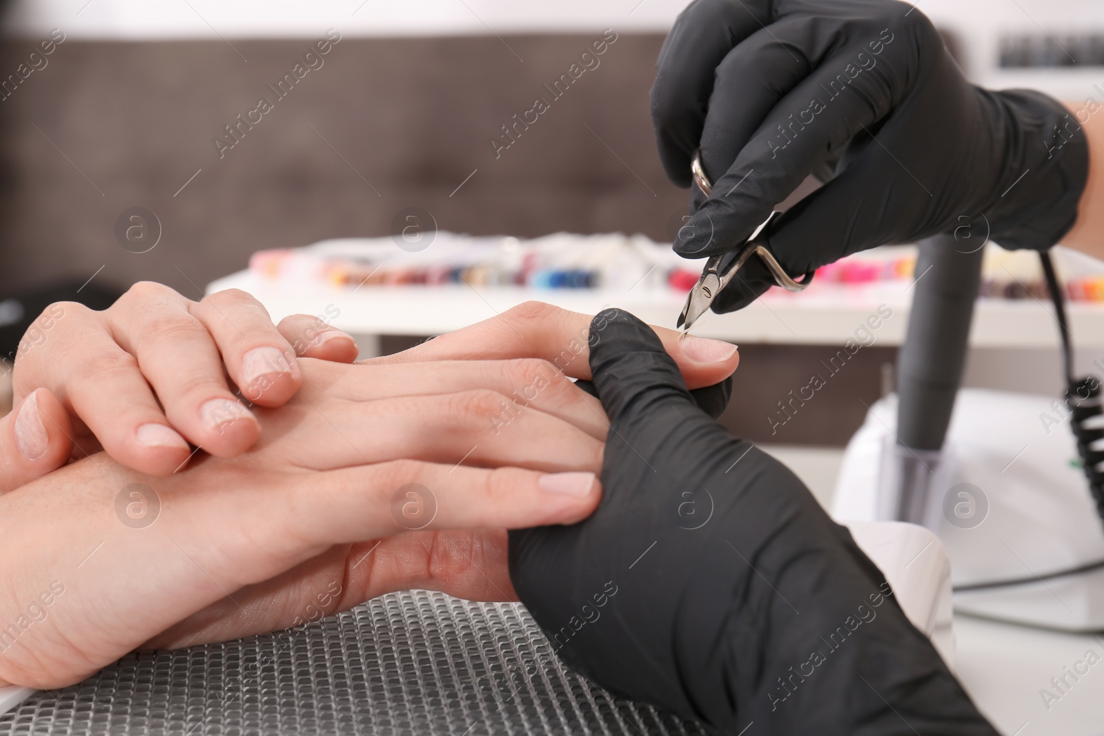 Photo of Professional manicurist working with client in salon, closeup