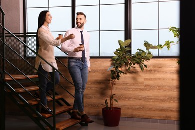 Photo of Coworkers talking during coffee break on stairs in office