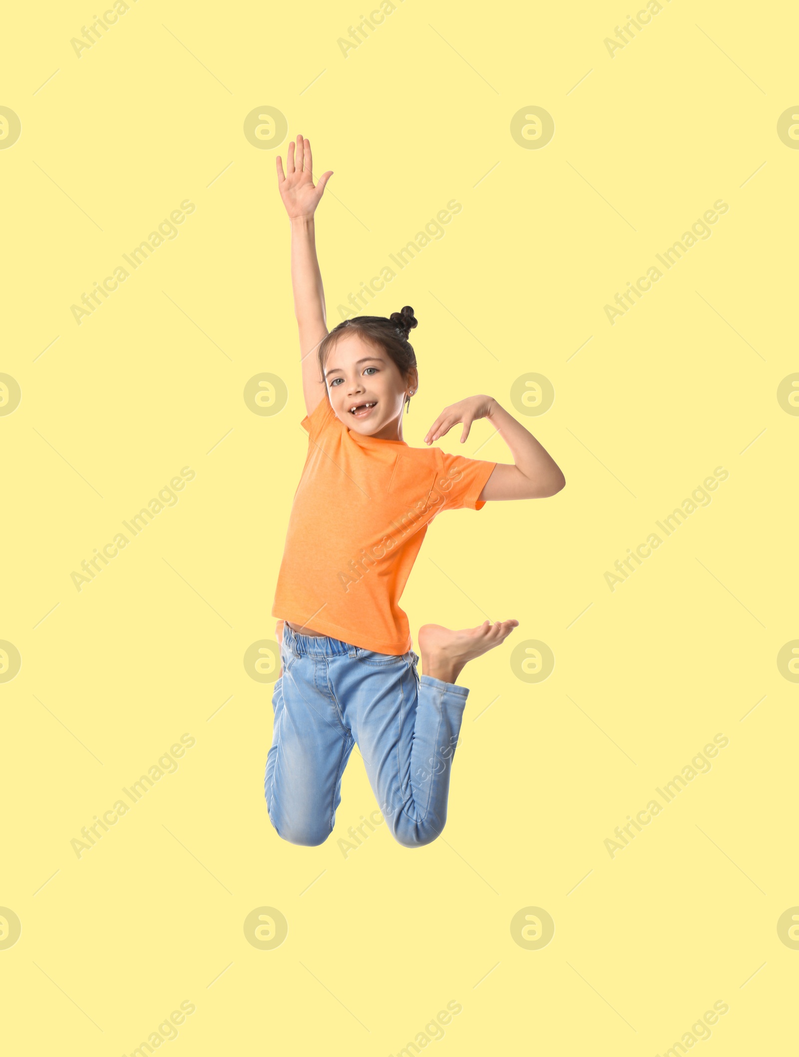 Image of Happy cute girl jumping on beige background