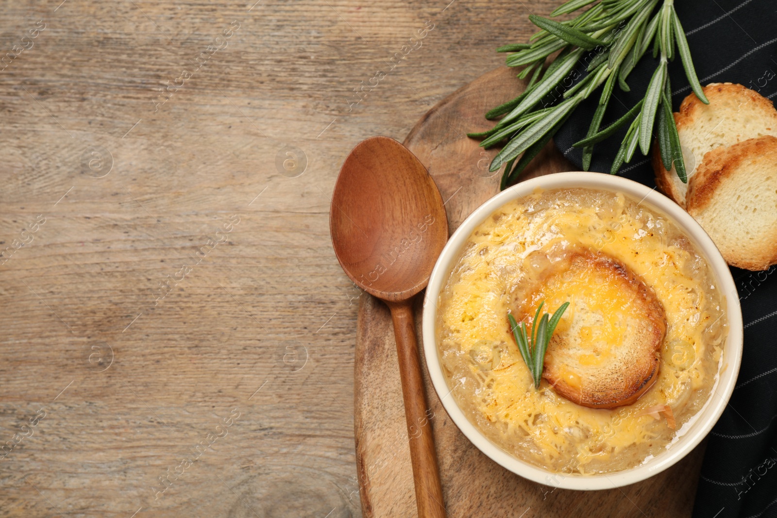 Photo of Tasty homemade french onion soup served on wooden table, flat lay. Space for text