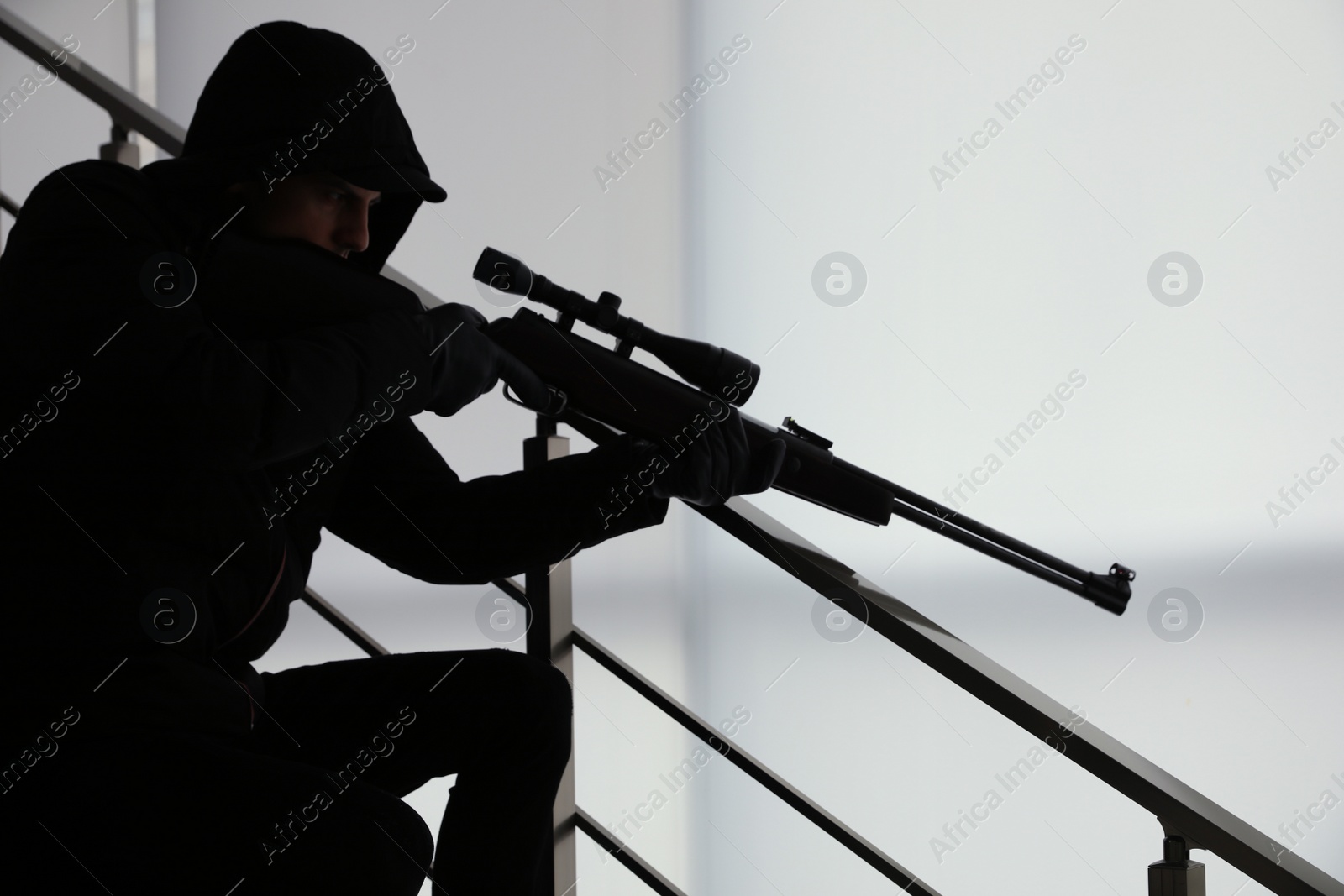 Photo of Hired professional killer with sniper rifle indoors
