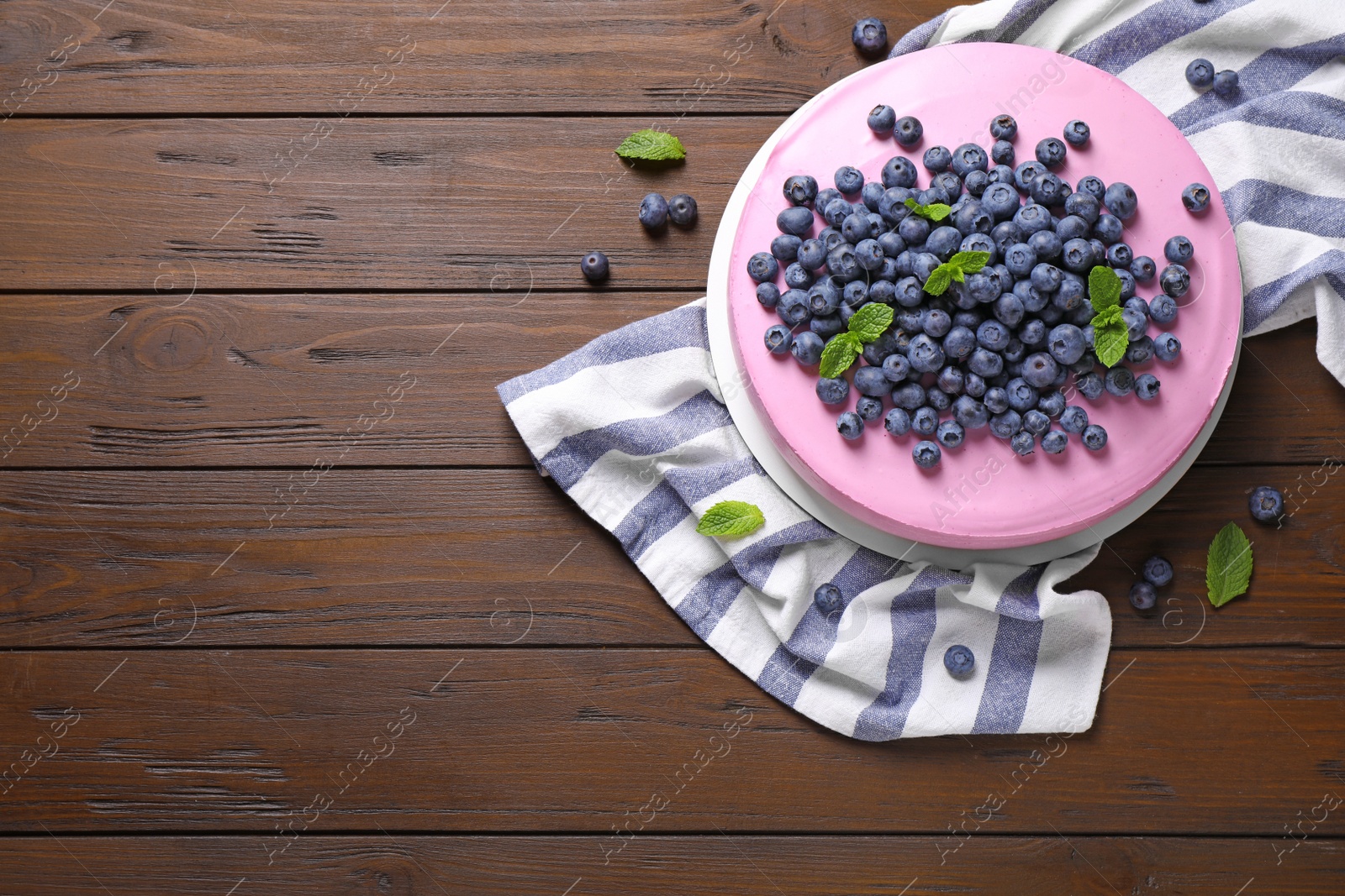 Photo of Tasty blueberry cake and napkin on wooden table, flat lay. Space for text