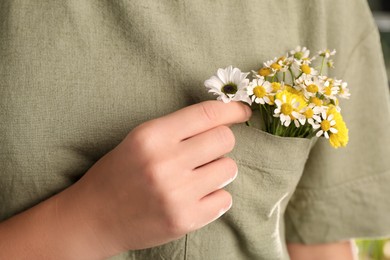 Photo of Woman with beautiful tender flowers in shirt's pocket outdoors, closeup